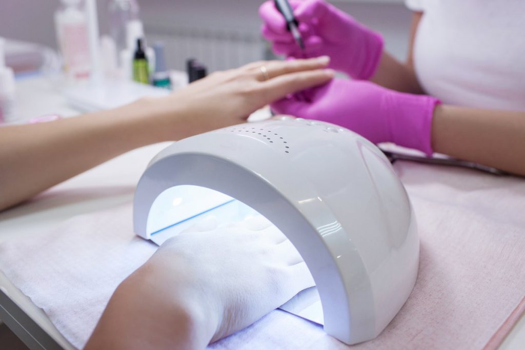 technician applying gel polish manicure