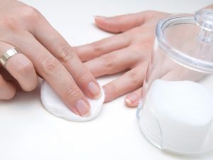 Close p of female hands using cotton pad to wipe finger nails